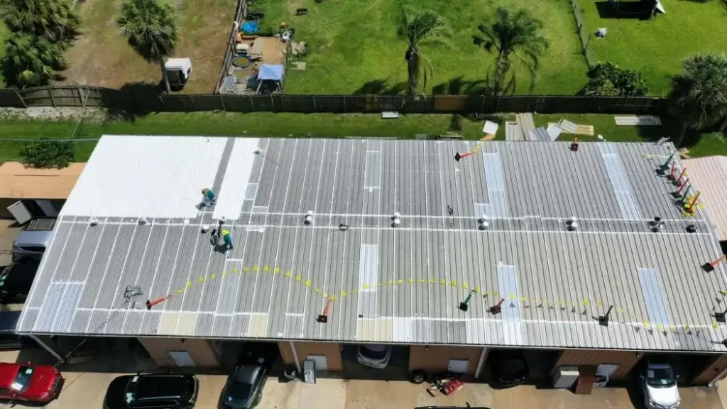 Aerial view of a large commercial building with a white metal roof featuring rectangular skylights