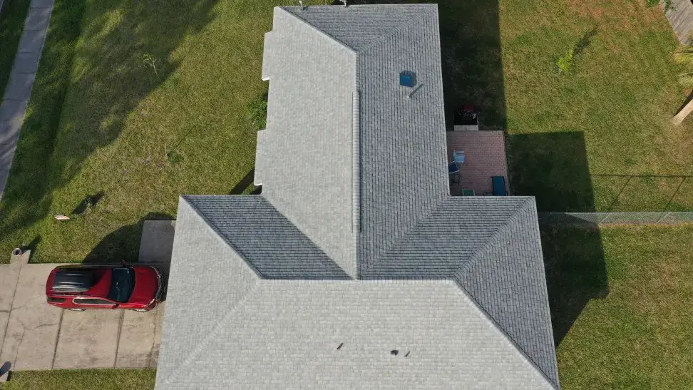 A house requiring roof maintenance, with a complex, multi-angled gray shingle roof.