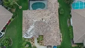 A residential house with a partly dismantled roof due to hail damage, showing visible construction materials and equipment.